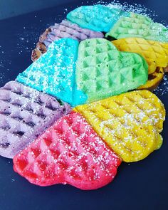 colorful waffles with powdered sugar on them are arranged in a rainbow pattern