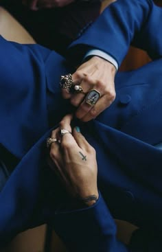 a person in a blue suit with two rings on their fingers and the other hand