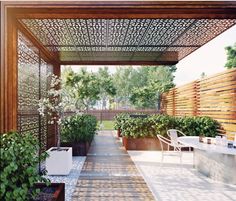 an outdoor dining area with potted plants and wooden pergolated roof over it