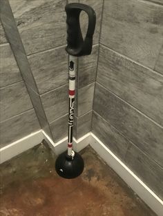 a black and white pole in the corner of a room with grey tiles on the walls