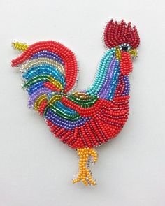 a colorful beaded rooster brooch sits on a white surface