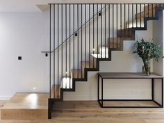 an empty room with some stairs and a vase on the table in front of it