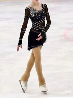 a female figure skating on the ice in a black dress with beading and pearls