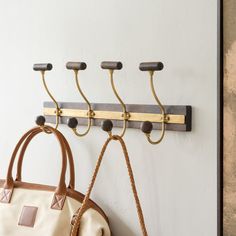 two purses hanging from hooks on a wall