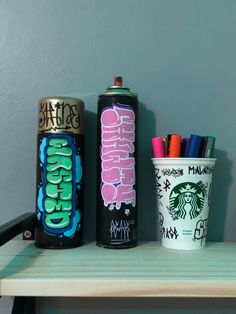 three different types of spray paint next to each other on a shelf with pens and pencils