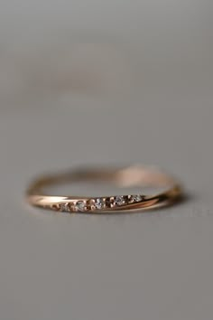 a gold wedding band with five diamonds on the top and bottom, sitting on a gray surface