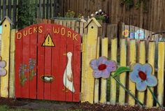 a wooden fence with flowers painted on it and a duck in the yard behind it