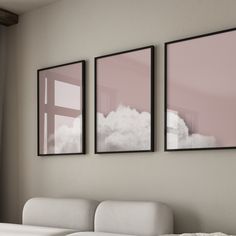 three framed pictures hang on the wall above a white couch in front of a window