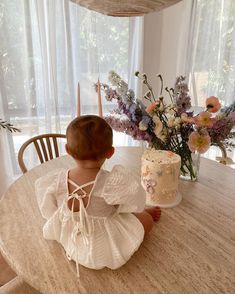 a small child sitting at a table with a cake