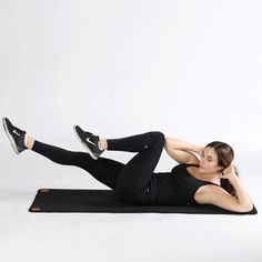 a woman is laying on a mat with her legs up and one leg in the air