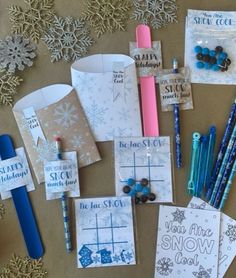 some cards and pens are laying out on the table with snowflakes around them