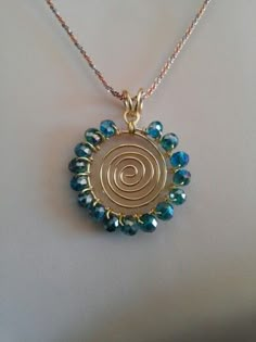 a gold necklace with blue beads and a spiral design