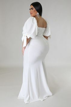 a woman in a white dress with her back turned to the camera and wearing large earrings