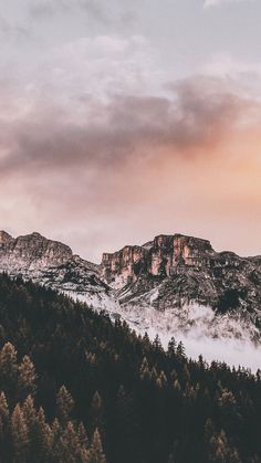 the mountains are covered in clouds and trees