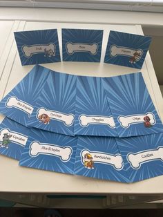 four blue paper place cards with paw patrol characters on them, sitting on a table