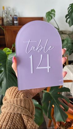 a person holding up a purple table number