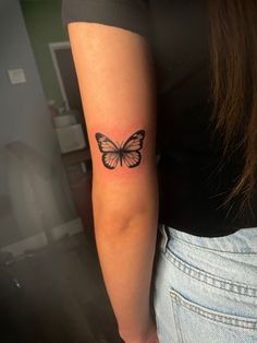 a woman's arm with a small butterfly tattoo on the back of her left arm