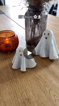 three ghost candles sitting on top of a table next to a vase filled with flowers