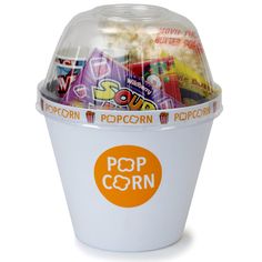 a cup filled with popcorn sitting on top of a white table next to an orange sticker