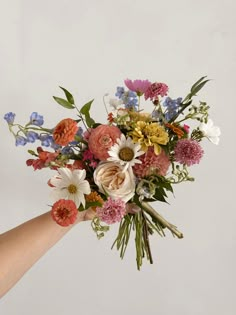 a person holding a bouquet of flowers in their hand