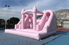 an inflatable pink castle on top of a tarp covered court with basketball hoop