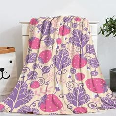 a pink and purple blanket sitting on top of a white table next to a potted plant