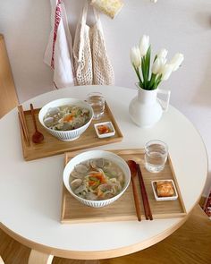 two bowls of soup sit on trays with chopsticks