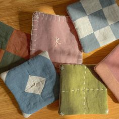 four different colored pillows sitting on top of a wooden table