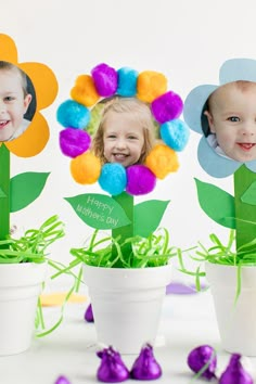 three potted plants with flowers in them and two children's faces on the top