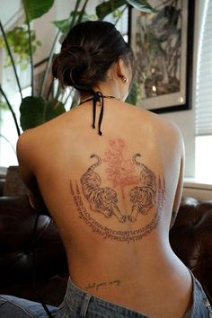 the back of a woman's body with tattoos on her upper and lower back