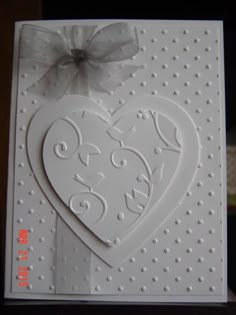 a white card with a heart on the front and a bow at the top,