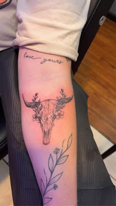 a person with a tattoo on their arm that has a cow skull and flowers in it