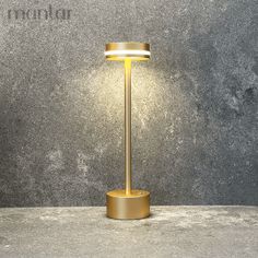 a lamp that is sitting on top of a cement floor next to a gray wall