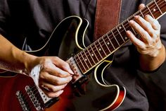 a close up of a person playing an electric guitar with his hands on the strings