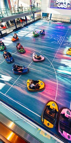 several people are riding bumper cars in an indoor area with colorful lights on the floor