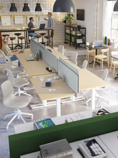 an office with people working on laptops and desks in the middle of it