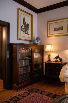 a living room with a bookcase, lamp and pictures on the wall above it