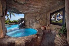 an indoor swimming pool in the middle of a cave with a tv on it's wall