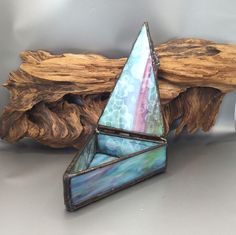 a small sailboat sitting on top of a piece of driftwood