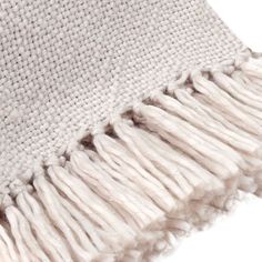 a white and beige blanket with fringes on it's edges, close up