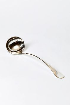 a silver spoon with a curved handle on a white surface