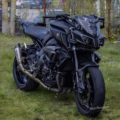 a black motorcycle parked on top of a lush green field