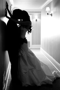 a bride and groom are kissing in the hallway at their wedding reception, black and white photograph