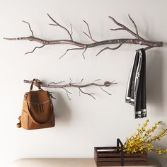 there is a purse hanging on the wall next to a tree branch with two hooks