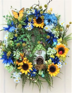 a wreath with sunflowers, daisies and other flowers hanging on a wall