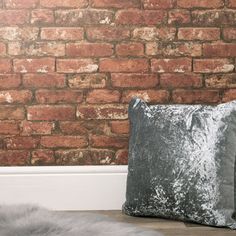 two velvet pillows sitting on top of a wooden table next to a red brick wall