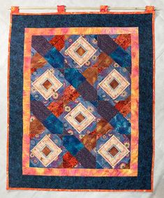 a blue and orange quilt hanging on a wall