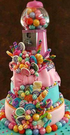 a multi layer cake with candy and gumballs on it's top, in the shape of a gumball machine