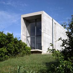 a concrete structure sitting on top of a grass covered hill next to trees and bushes