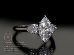 an engagement ring with two pear shaped diamonds on it's side and the center stone is